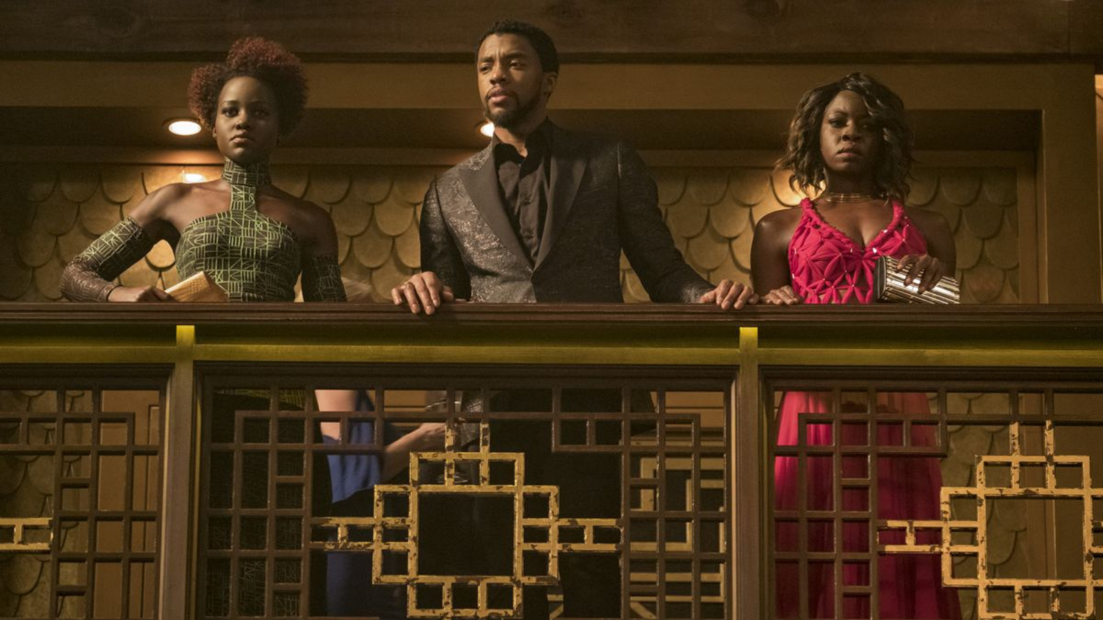 Nakia in a green dress, T'Challa in a black suit, Okoye in a red dress from the casino scene in Black Panther.