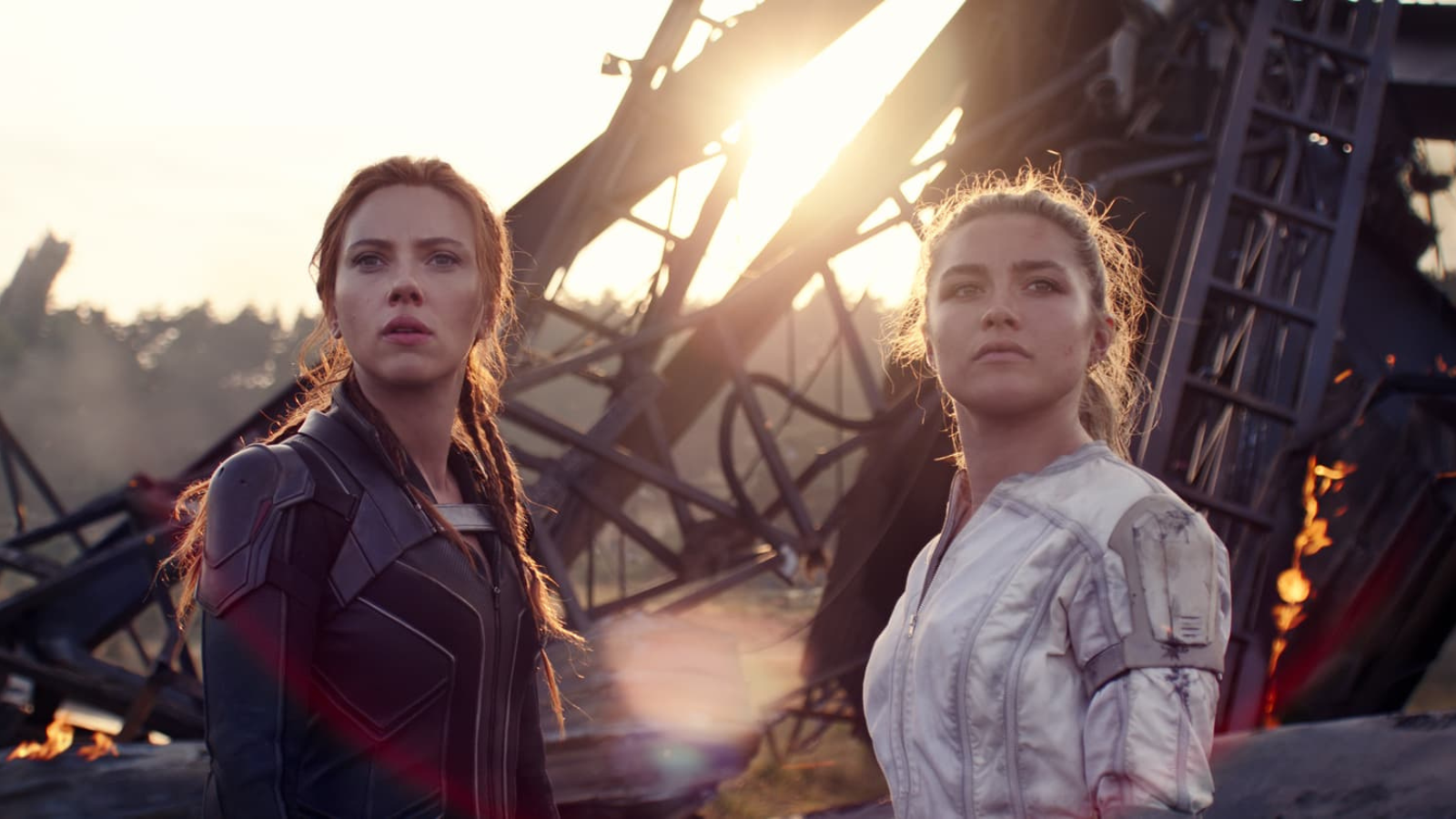 Natasha Romanov in one of her signature skin tight Black Widow suits and Yelena Belova in a white suit which is baggy on her. Both of them have mussed hair.